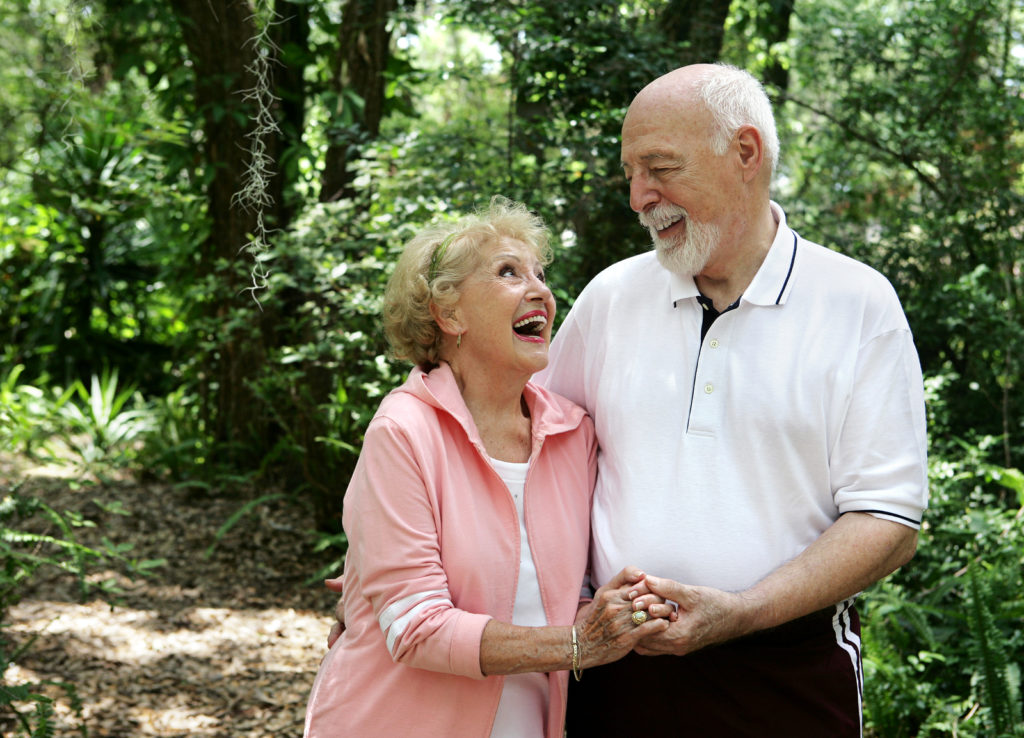 A happy active senior couple laughing together on a walk through the park in Laguna Hills, CA.