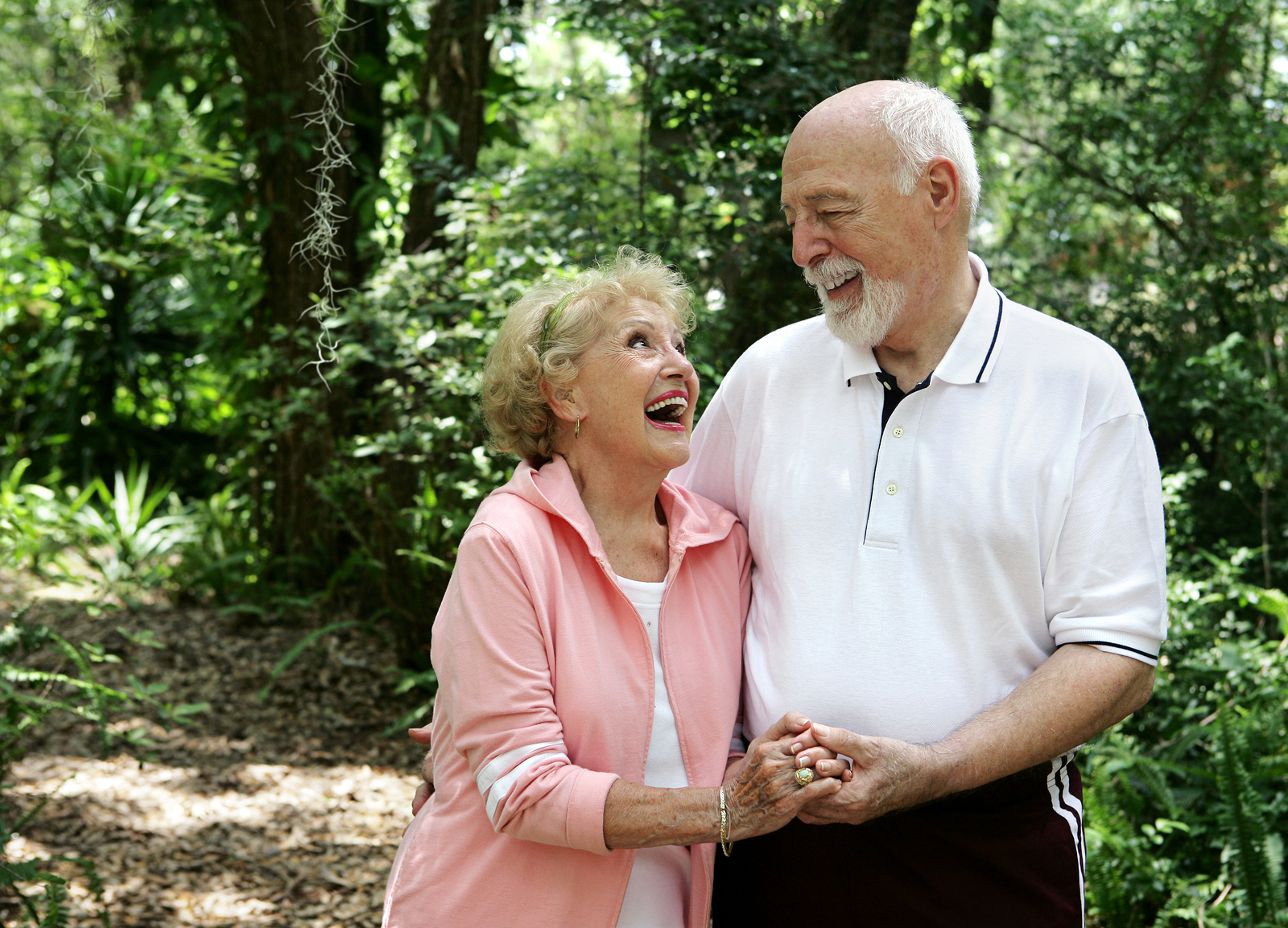 A happy active senior couple laughing together on a walk through the park in Laguna Hills, California.